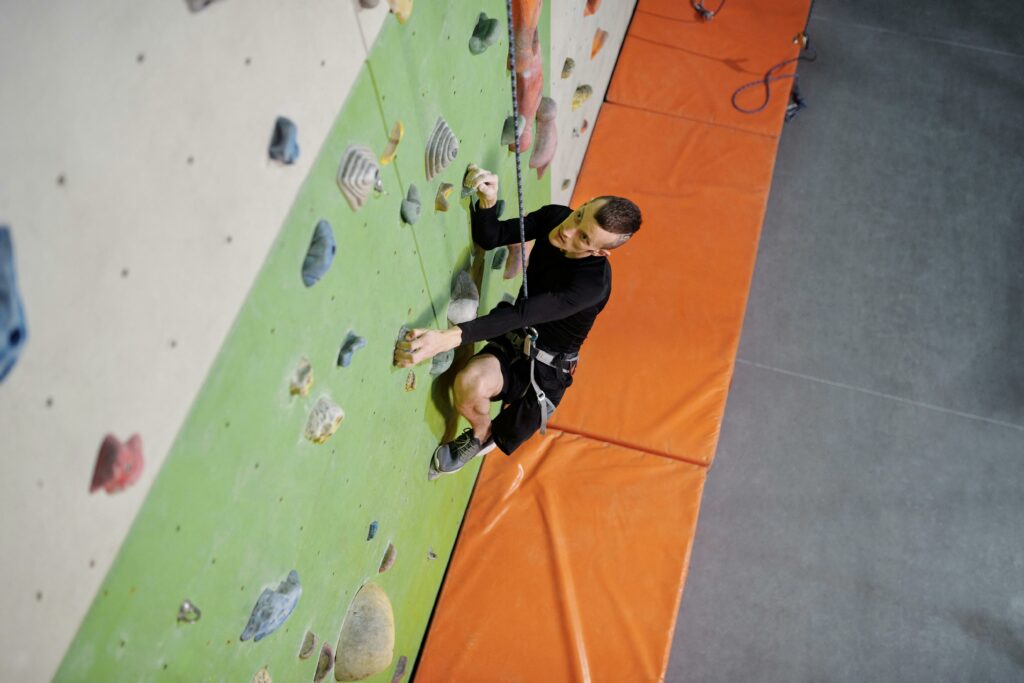 ATELIERS Man with prosthetic leg rock climbing indoors, showcasing determination and strength.
