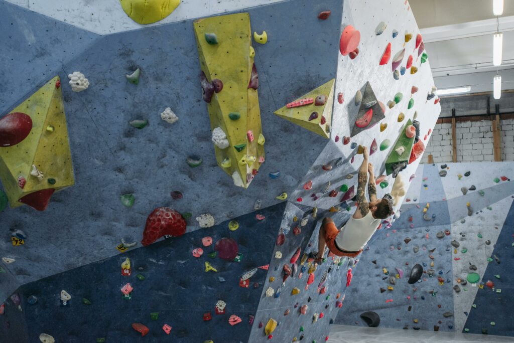 ATELIERS Focused athlete climbing an indoor bouldering wall, showcasing strength and agility.